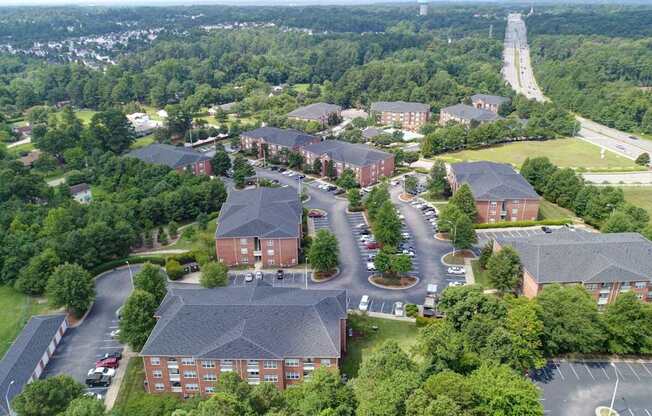 A large red brick building surrounded by trees and a parking lot.
