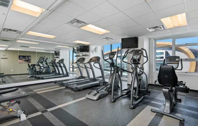 a gym with treadmills and other exercise equipment in a room with windows