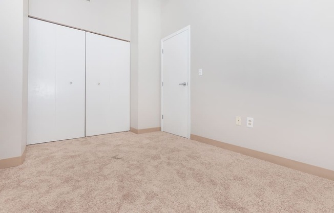 a room with carpet and white walls and doors