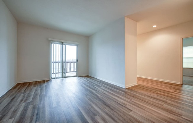 an empty living room with wood flooring and a balcony