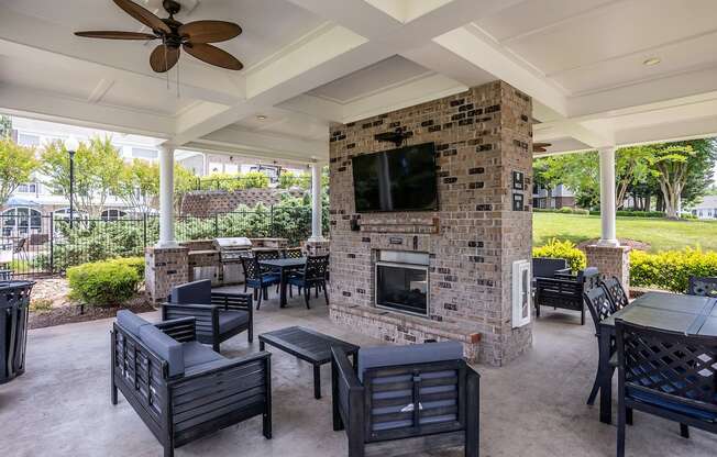 a covered patio with a fireplace and tables and chairs
