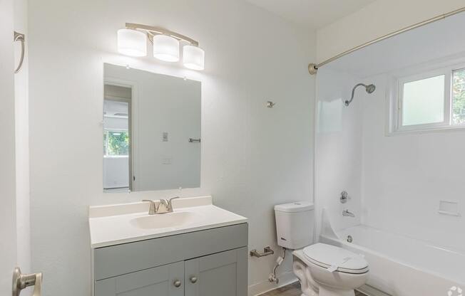 A white bathroom with a toilet, sink, and mirror.
