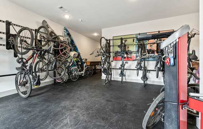 a room with many bikes hanging on a wall and a red door
