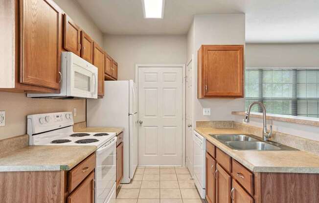 A kitchen with white appliances and wooden cabinets.