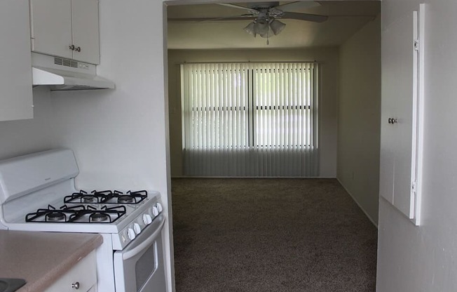 an empty kitchen with a stove and a ceiling fan