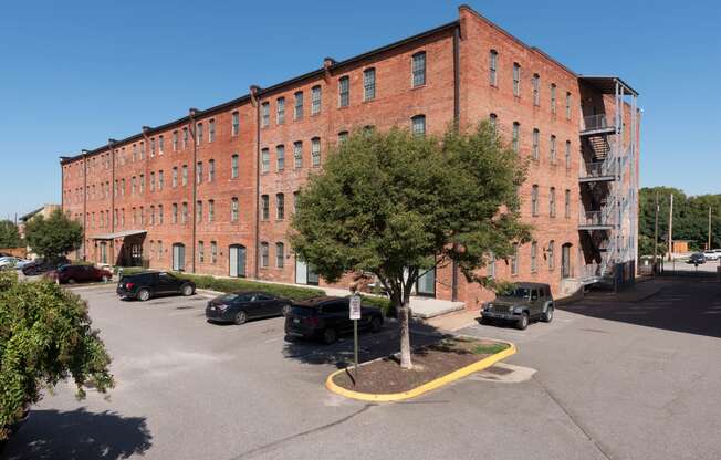 the side of a brick building with cars parked in a parking lot at Mayton Transfer Lofts, Petersburg