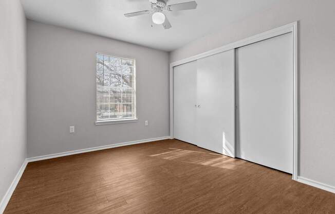 A room with a ceiling fan and a window with blinds.