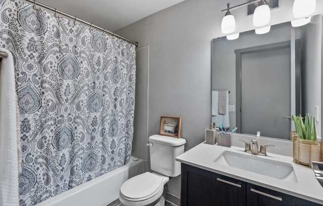 A bathroom with a toilet, sink, and shower curtain.