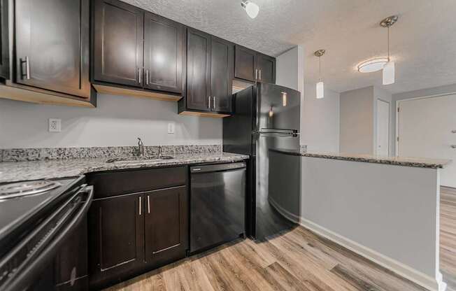 A kitchen with black cabinets and a stainless steel refrigerator.