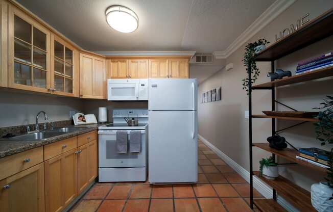 Model unit kitchen with spacious wooden cabinets, granite countertops, and electric appliances at the Atrium Apartments in San Diego, California.