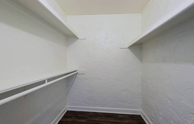A white wall with a wooden floor and a white shelf.