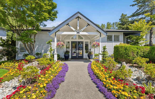 A white house with a grey roof and a gravel pathway leading to the front door.