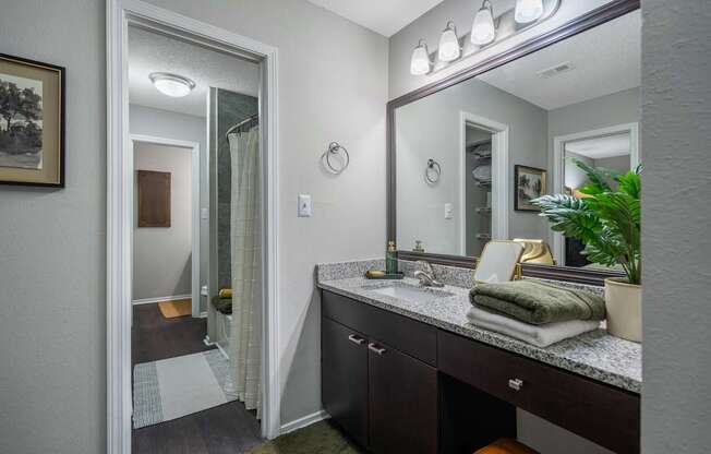 A bathroom with a vanity, mirror, and lights.