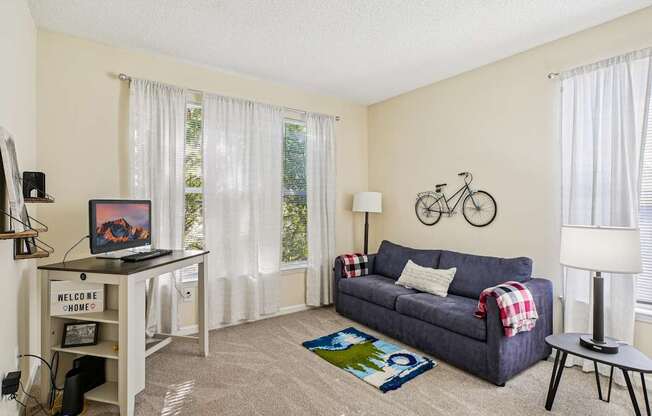 A living room with a couch, a table, and a bicycle on the wall.