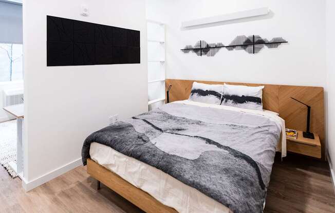 a bedroom with white walls and a bed with a gray blanket