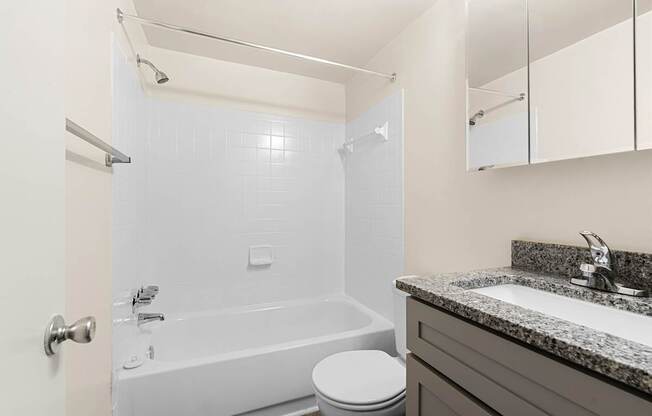 A white bathroom with a toilet, sink, and bathtub.