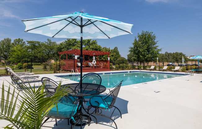 a swimming pool with a table and chairs under an umbrella