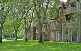 a large grassy area with trees in front of a building