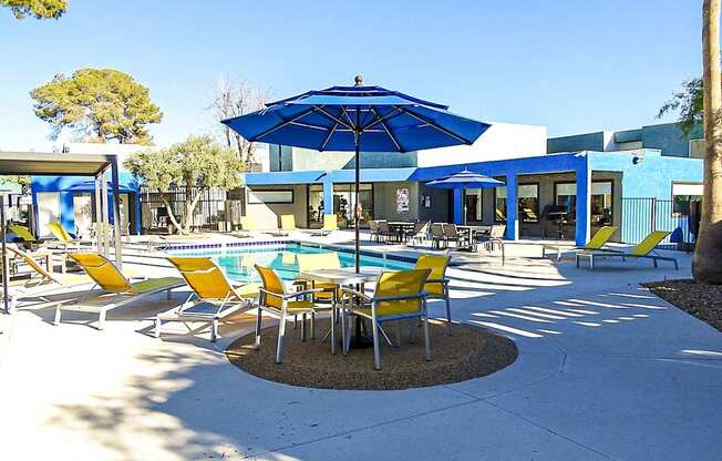 A blue umbrella is in the middle of a table and chairs.