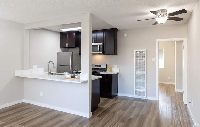 A kitchen with a white counter top and black cabinets.