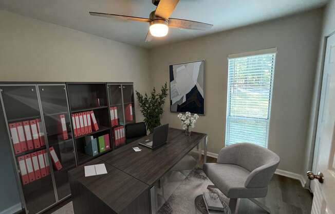 a home office with a desk and chair and a ceiling fan