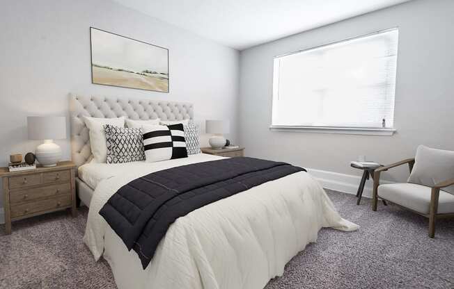 a bedroom with grey carpet and a large bed with black and white pillows