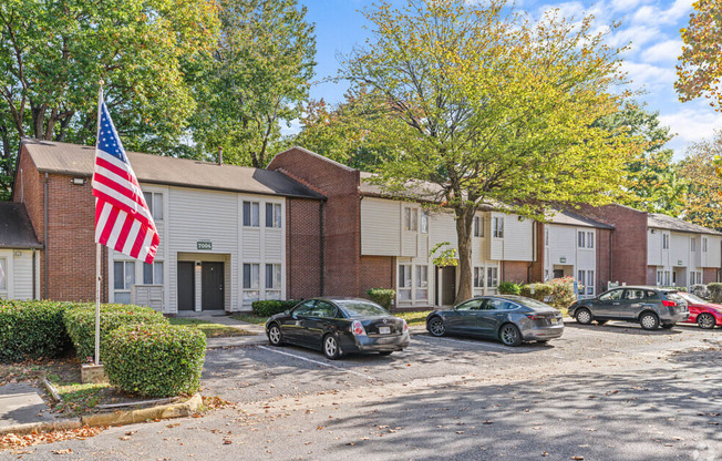 an flag flies in front of an apartment building with cars parked in front