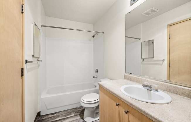 a bathroom with a toilet sink and bathtub  at Mill Pond Apartments, Auburn, WA 98092