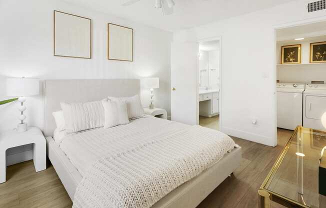 a white bedroom with a large bed and a bathroom