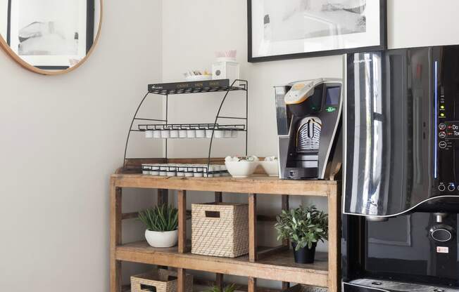 a shelf with baskets and plants next to a coffee machine in a living room