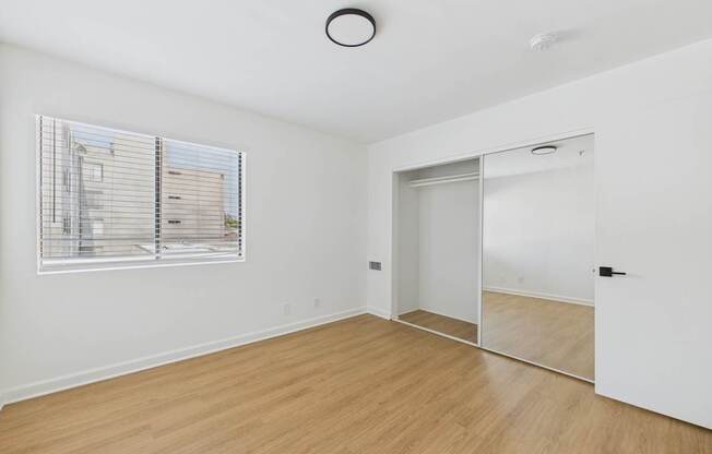 A room with a white wall and a window with blinds.