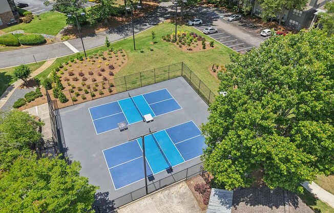 tennis courts surrounded by a fence and trees.