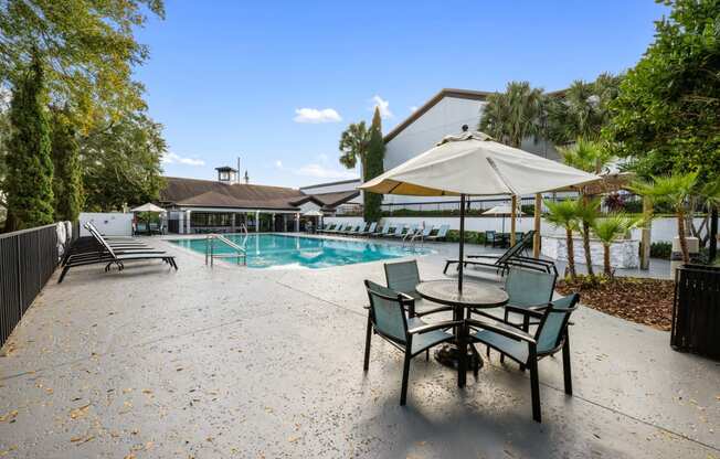 a swimming pool with a patio with chairs and an umbrella