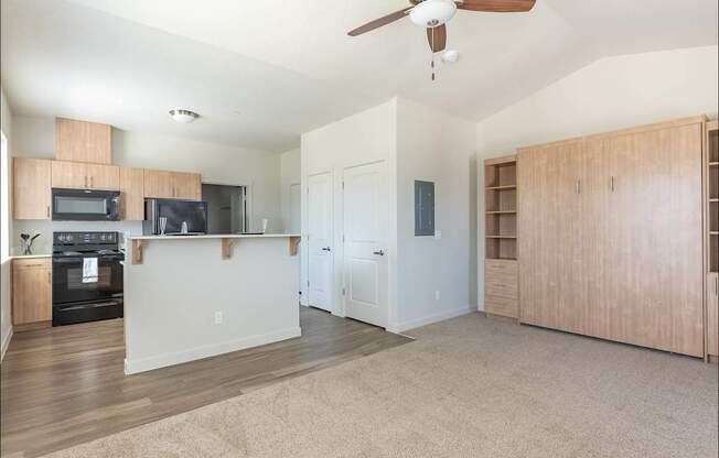 A living room with a ceiling fan and a kitchen area with a microwave and oven at Forestplace Apartment Homes, Forest Grove, OR