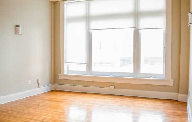 an empty living room with wood floors and a large window