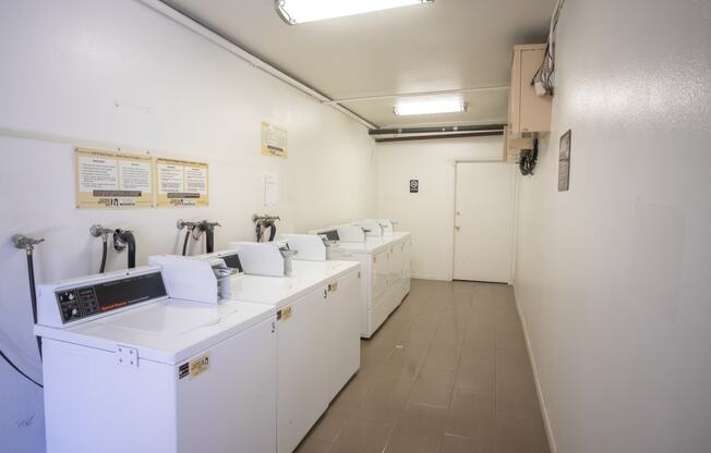 a laundry room with four washers and dryers and a row of washing machines