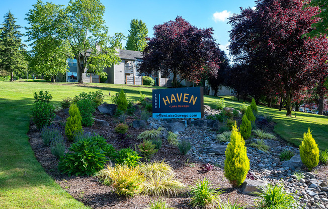 A garden with a sign that says "HAVEN" in front of a house.