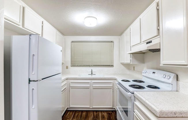 a kitchen with white cabinets and white appliances and a refrigerator