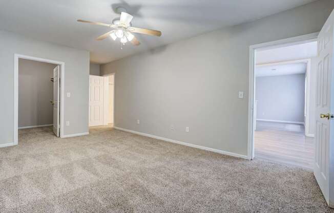 A spacious room with a ceiling fan and carpeted floor.