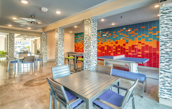 a dining area with tables and chairs and a colorful wall with tiles