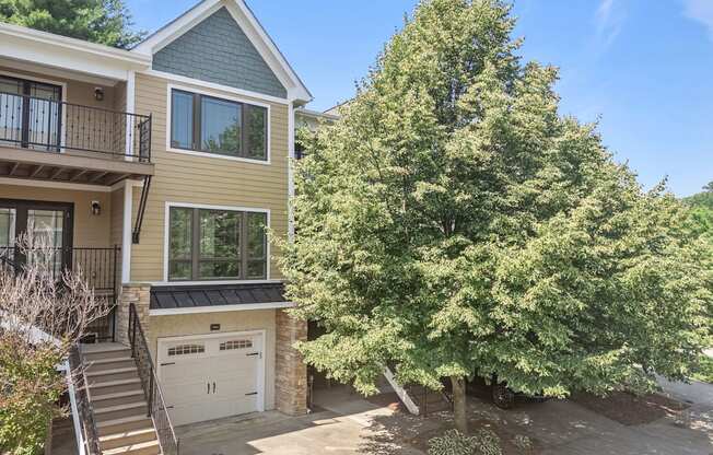 A house with a garage and a tree in front.