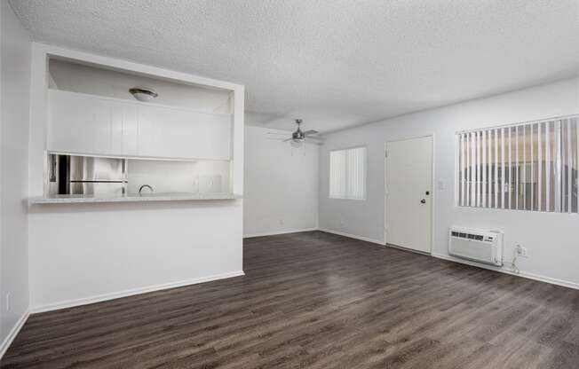 an empty living room and kitchen with white walls and wood flooring