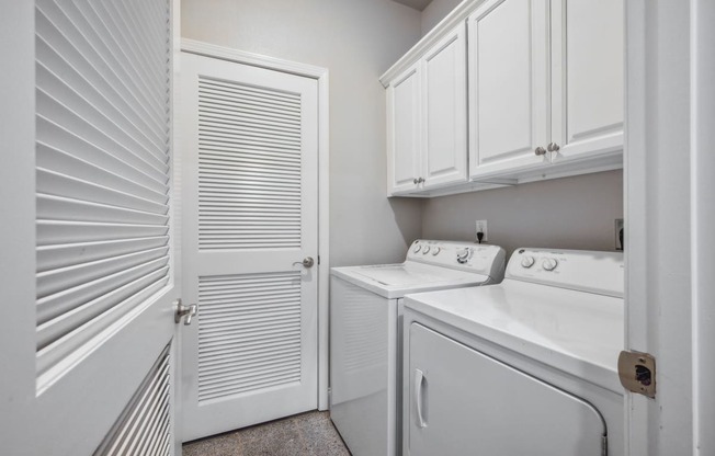 a laundry room with a washer and dryer and white cabinets