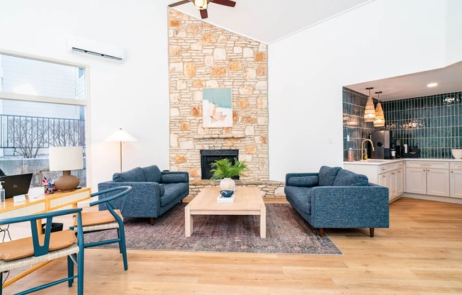 A living room with a stone fireplace and a blue couch.