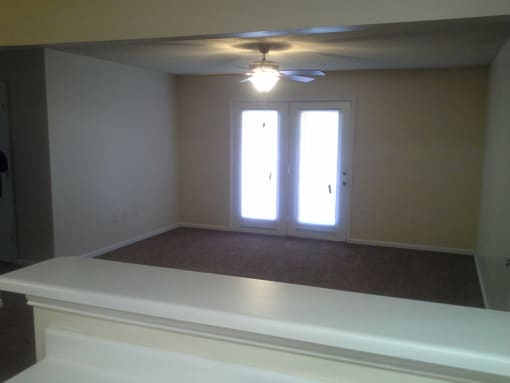 an empty living room with a ceiling fan