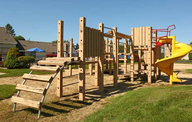 a playground with a yellow slide and wooden steps