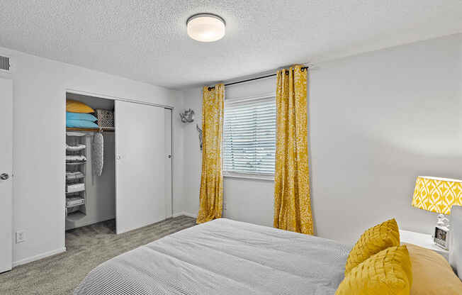 a bedroom with a bed and yellow curtains and a closet