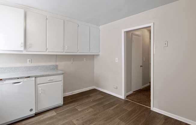 an empty kitchen with white cabinets and a door to a closet