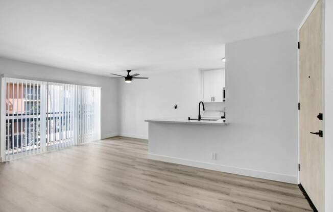 an empty living room with a kitchen and a balcony