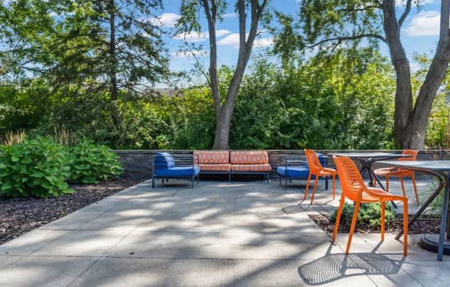 A patio with orange chairs and a blue bench.